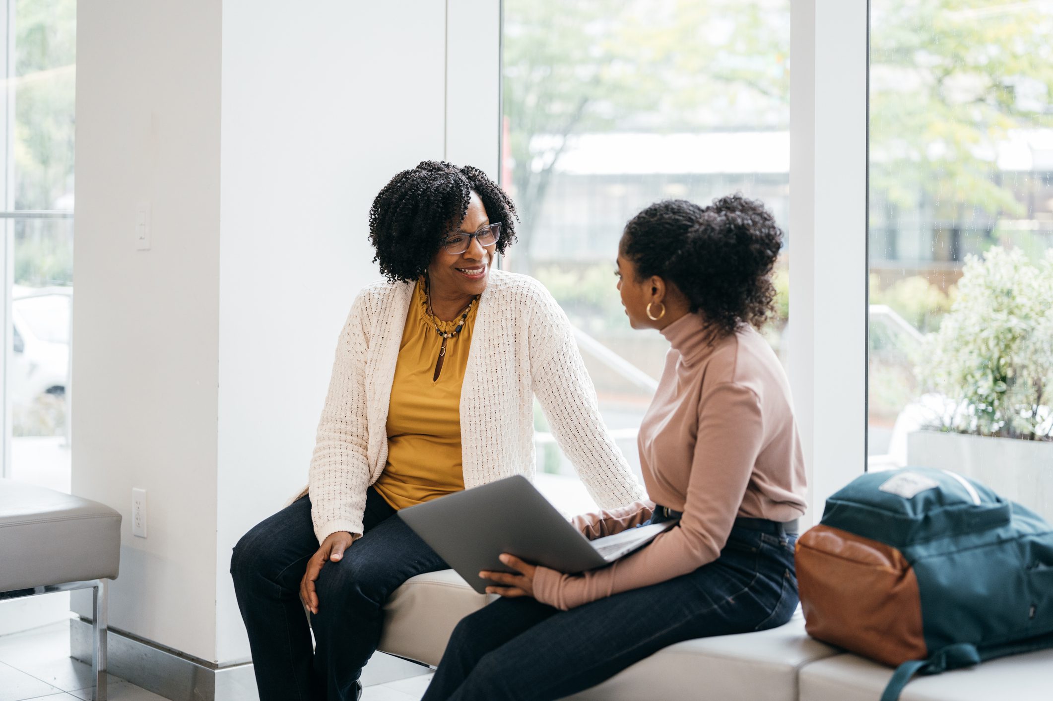 Two women engaged in a friendly conversation with a laptop.