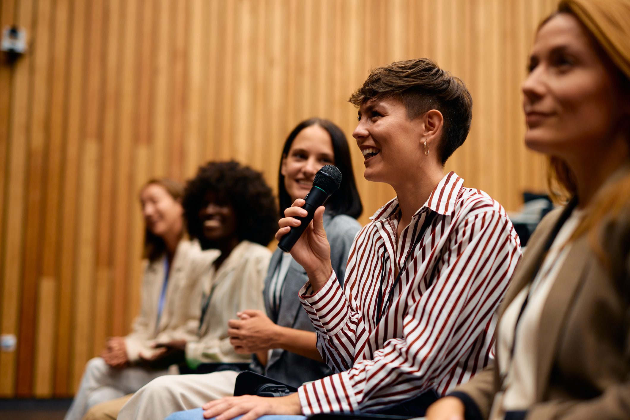Young woman speaking into a microphone at a panel discussion.